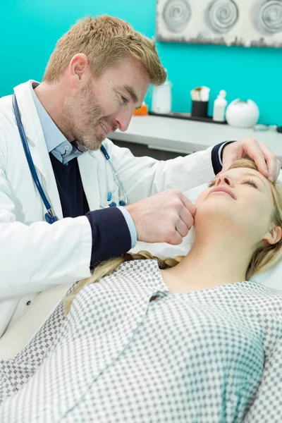 Kosmetolog läkare undersöker patienter ansikte — Stockfoto