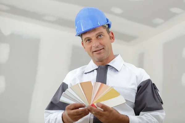 Mann Bauarbeiter hält eine farbige Uhr in der Hand — Stockfoto