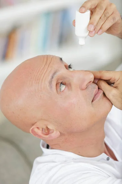 Hombre aplicando gotas para los ojos a sus ojos — Foto de Stock