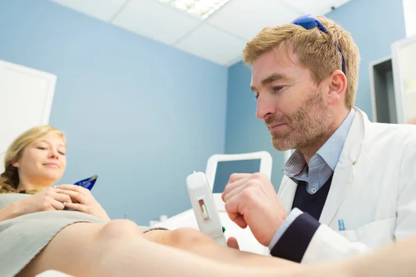 Jong aantrekkelijk meisje verwijderen van haar uit benen met laser — Stockfoto