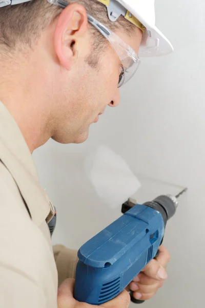 Mid-adult male builder drilling hole in wall — Stock Photo, Image