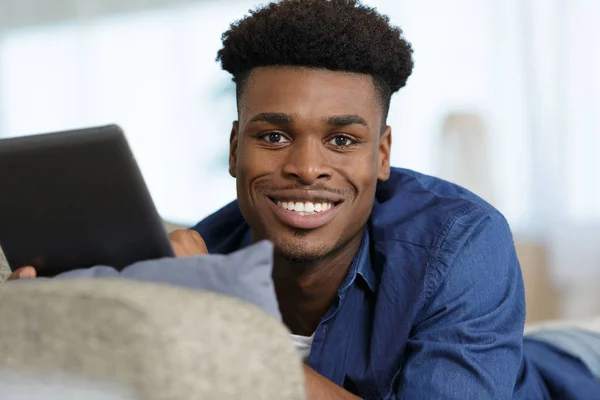 젊은 남자 누워 에 소파 와 행복 와 태블릿 — 스톡 사진