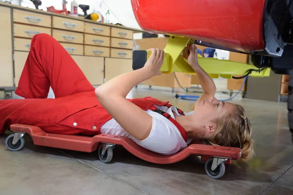 Mecánico mintiendo y trabajando bajo el coche — Foto de Stock