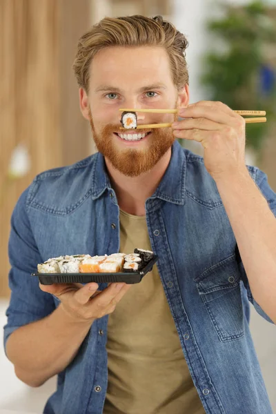 Jovem feliz comendo sushi — Fotografia de Stock