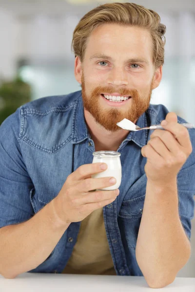 Mangiare sano giovane uomo yogurt in cucina — Foto Stock