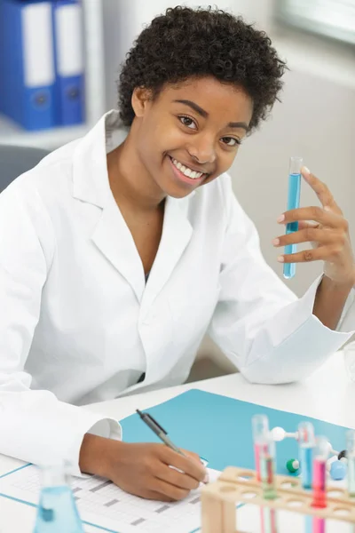 positive minded woman smiling while looking at a test tube