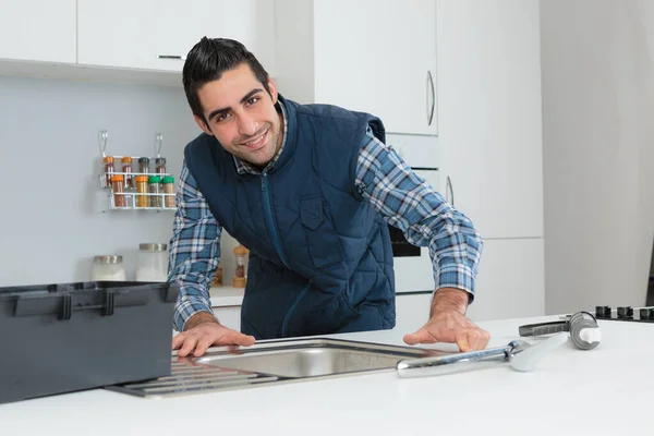 Работник устанавливает кран в кухонной раковине — стоковое фото