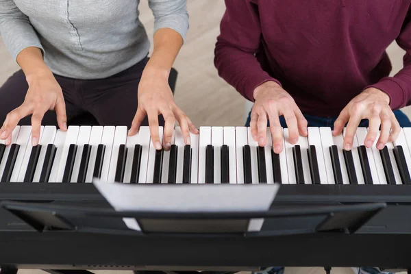Чотири руки грають на клавішах піаніно — стокове фото