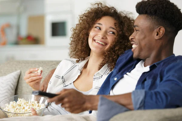 Pareja joven con palomitas de maíz en el sofá viendo una película —  Fotos de Stock