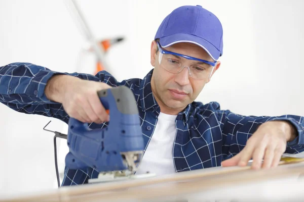 Homem cortando bloco de madeira com fretsaw — Fotografia de Stock