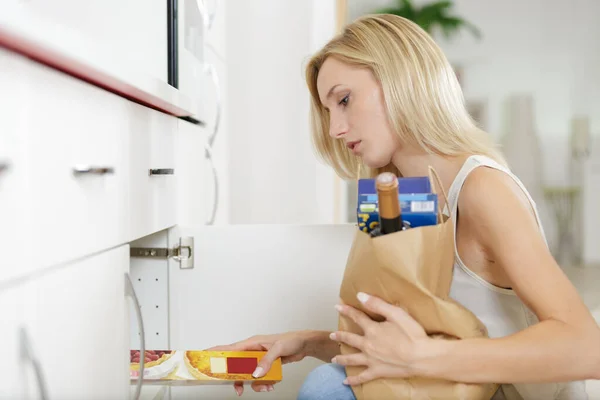 Frau legt ihre Einkäufe in der Küche ab — Stockfoto