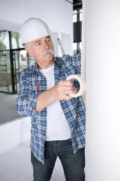 Senior contractor applying tape to wall — Stockfoto