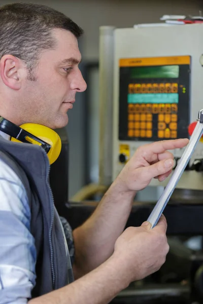 Reifer Mann mit Klemmbrett in einer Fabrik — Stockfoto