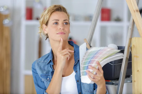 Vrouw kiezen kleur voor muur van stalen in de kamer — Stockfoto