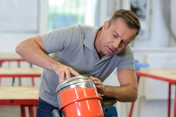 Mann überprüft einen metallenen Gegenstand — Stockfoto