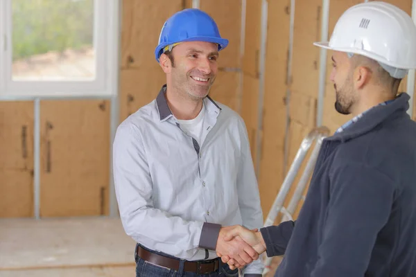 若い男性建築家と建設労働者が握手をし — ストック写真