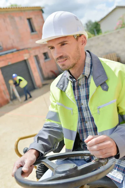 Trabajador masculino feliz que opera excavadora en el sitio de construcción — Foto de Stock