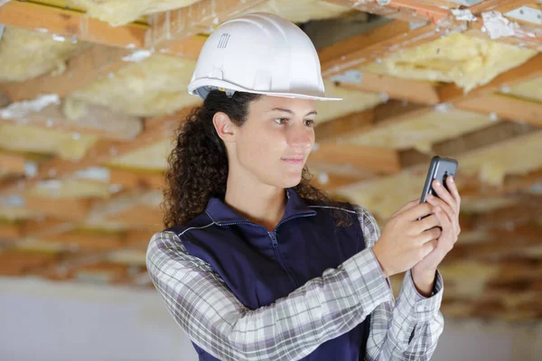 Female builder using smartphone inside property under renovation — Stock Photo, Image