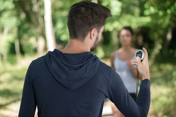 Personlig tränare timing en kvinnlig löpare — Stockfoto