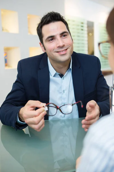 Чоловік купує окуляри в оптичному магазині — стокове фото