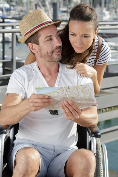 Handikappad man i rullstol visar karta till hustru — Stockfoto