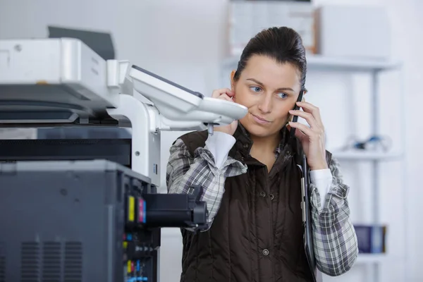 Fêmea verificando uma impressora defeituosa — Fotografia de Stock