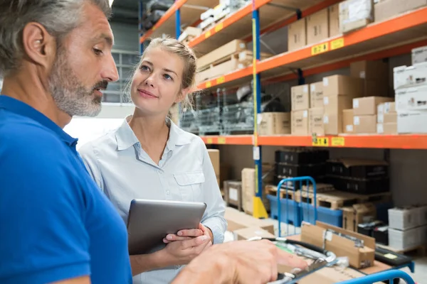 Lagerarbetare i diskussion och innehav av digitala tablet — Stockfoto