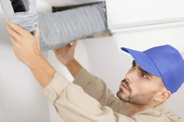 Een werknemer die ventilatieslang installeert — Stockfoto