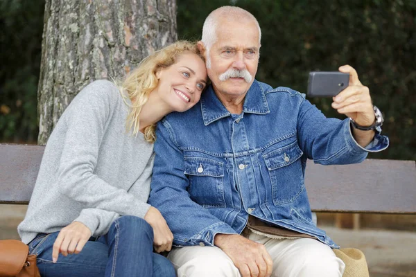 Ηλικιωμένος άντρας που βγάζει μια φωτογραφία με μια νεαρή γυναίκα — Φωτογραφία Αρχείου