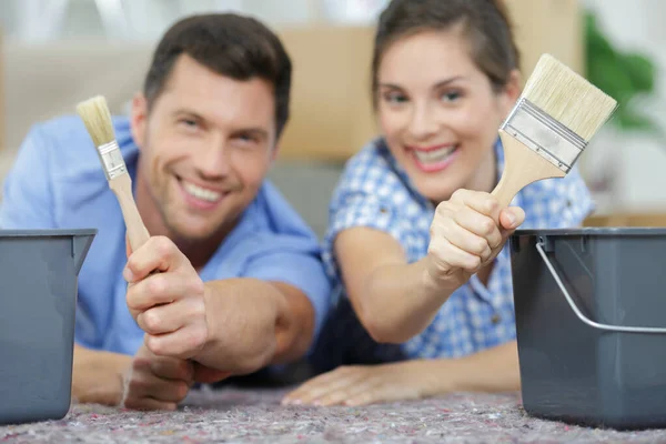 Couple are sitting on the floor with paint brushes — Stock Photo, Image