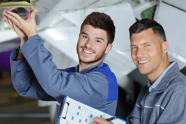 Twee monteurs die aan een vliegtuig werken in een hangar — Stockfoto
