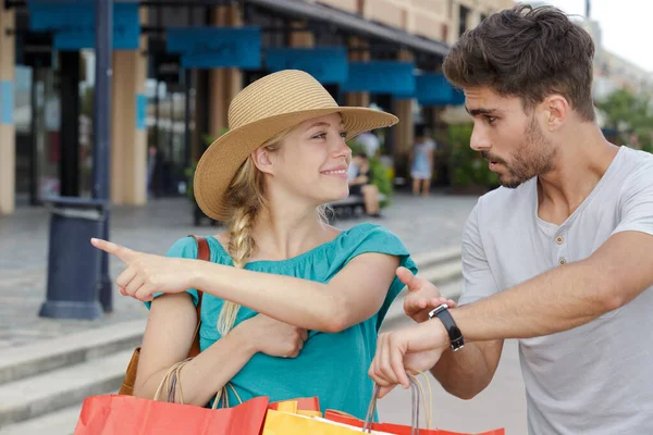 Man looking at watch as girlfriend want to continue shopping — Stock Photo, Image