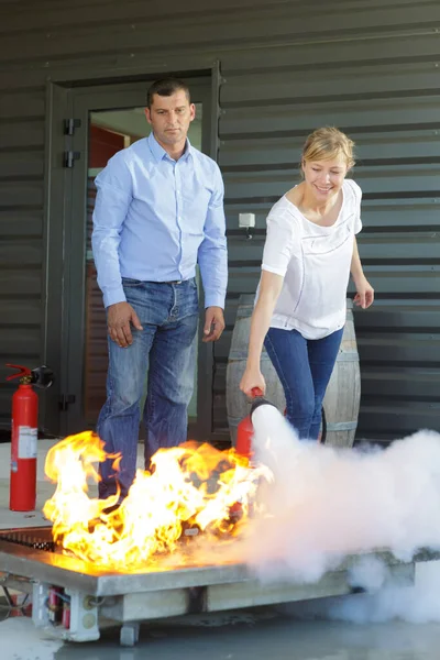 Mujer que demuestra cómo utilizar un extintor de incendios —  Fotos de Stock