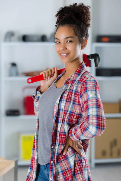 Smiling woman builder holding a tool on shoulder — ストック写真