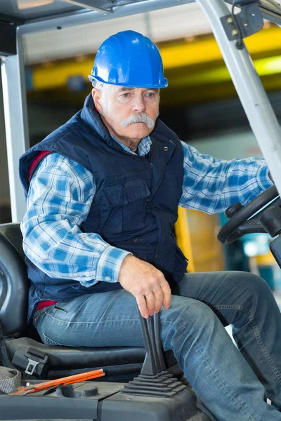 Starší muž nebo nakladač obsluhující vysokozdvižný vozík ve skladu — Stock fotografie
