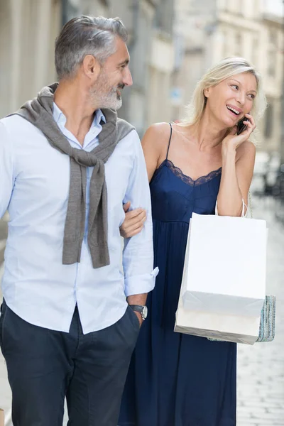 Улыбающиеся муж и жена на улице на мобильный телефон — стоковое фото