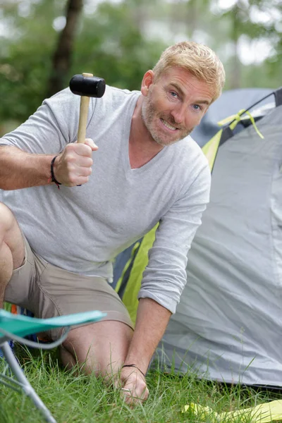 男人用橡胶木槌敲打帐篷的木桩 — 图库照片