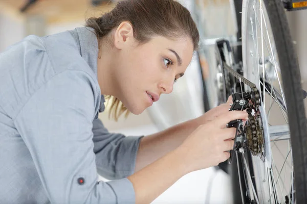 自転車で女性の整備士が車輪を修理し — ストック写真