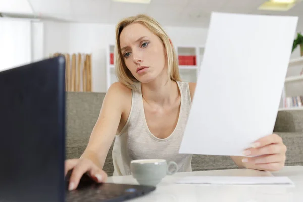 Frau Hause Hält Papier Der Hand Und Tippt Auf Laptop — Stockfoto