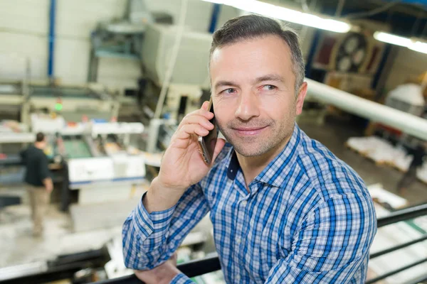 工場で電話で話すハンサムな成熟したビジネスマンの肖像画 — ストック写真