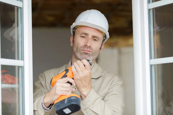 Mužský Pracovník Kontrolující Svůj Vrták Před Opravou Okna — Stock fotografie