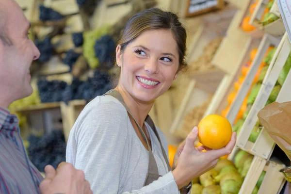 Asistente Tienda Sonriente Sosteniendo Naranja — Foto de Stock