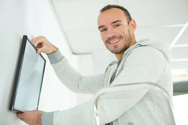 Homem Sorrindo Enquanto Pendurado Quadro Parede — Fotografia de Stock