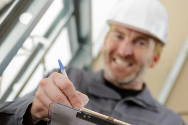 Lächelnder Arbeiter Zeigt Ein Klemmbrett — Stockfoto