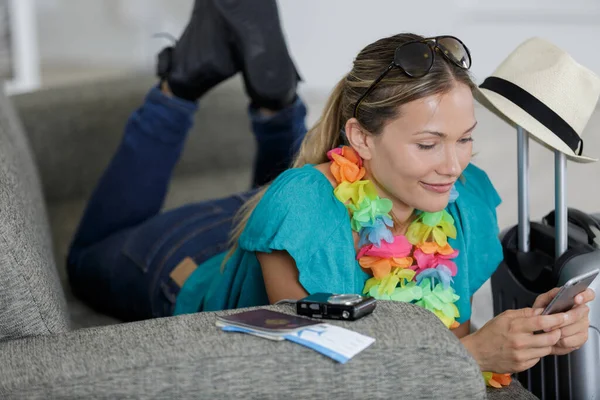 Vrouw Liggend Bank Met Reizen Accessoires Met Behulp Van Smartphone — Stockfoto