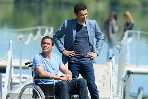 車椅子で友人と話す障害者は — ストック写真