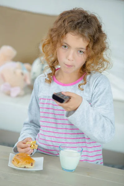 Niña Sosteniendo Control Remoto Mientras Come — Foto de Stock