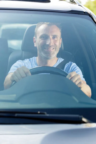 自信のある男が新しい車の車輪に座って — ストック写真