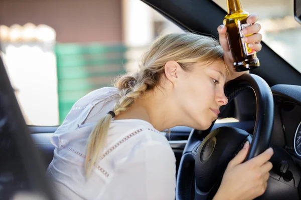 Γυναίκα Οδηγός Slouched Πάνω Από Τιμόνι Κρατώντας Μπουκάλι Μπύρα — Φωτογραφία Αρχείου