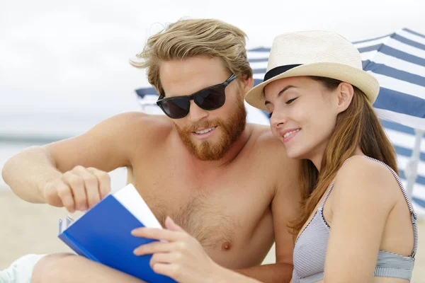 ビーチで本を読んでいるカップルは — ストック写真